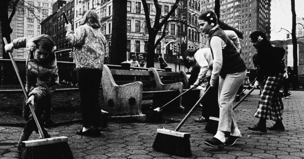 کودکان از جاروهای فشار برای جارو کردن یک پارک شهر نیویورک در روز زمین استفاده میکنند .