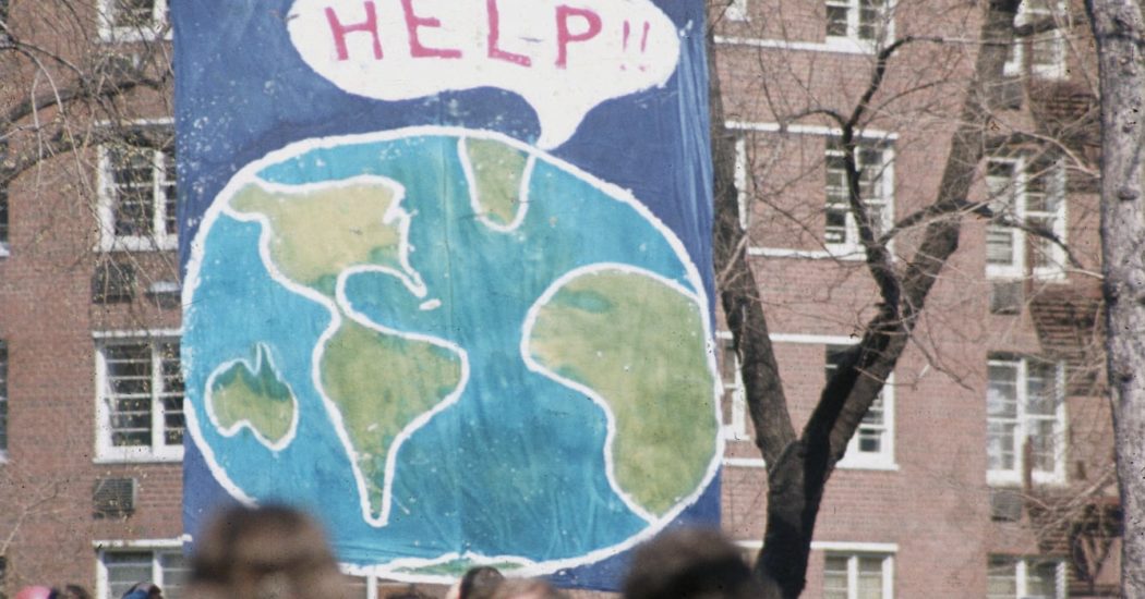 جمعیت زیادی در نیویورک در نزدیکی پوستر بزرگ هستند که حباب گفتار از سیاره زمین را نشان میدهد که میخواند " کمک !!"